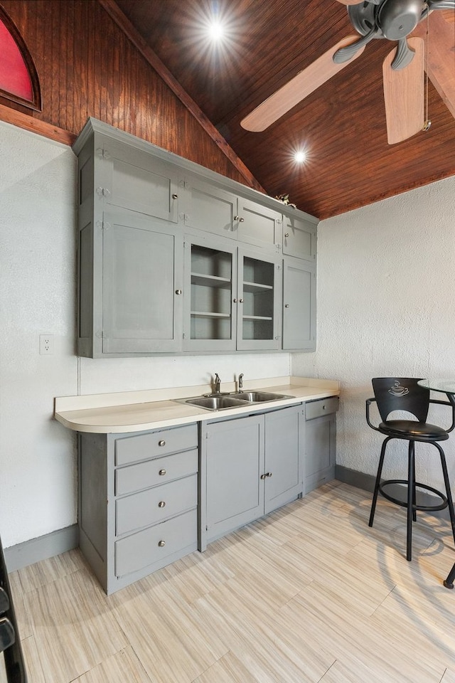 kitchen featuring gray cabinets, lofted ceiling, sink, and wooden ceiling