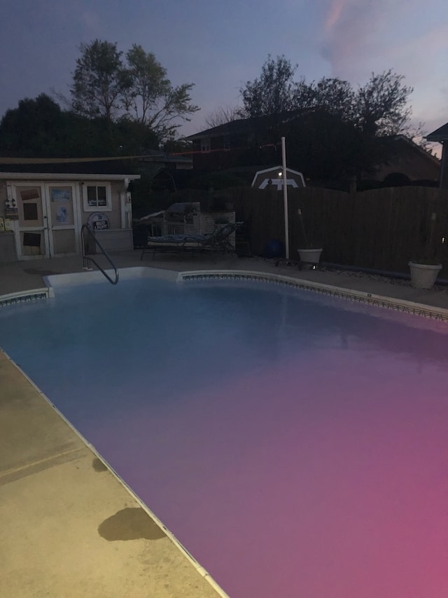 pool at dusk featuring a patio