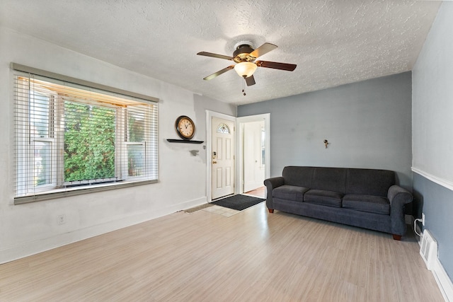 living room featuring light hardwood / wood-style floors, a textured ceiling, and ceiling fan