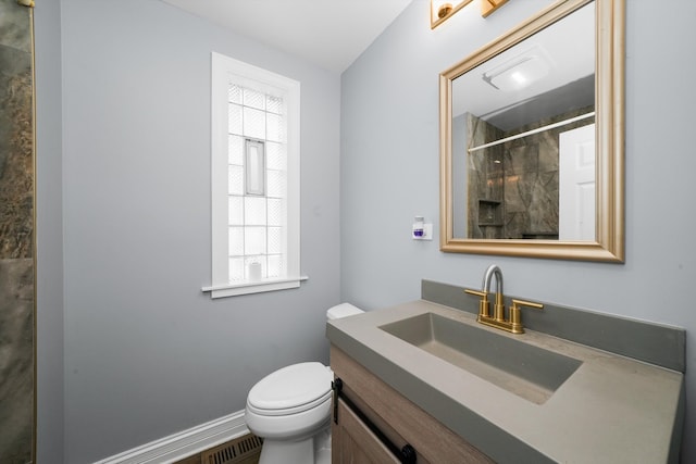 bathroom featuring vanity, toilet, and a tile shower