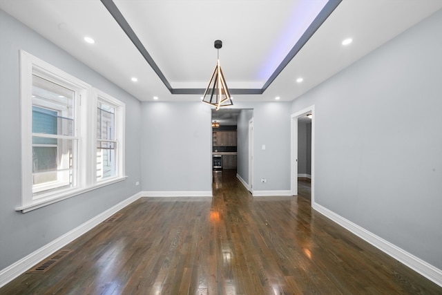 interior space featuring a tray ceiling and dark hardwood / wood-style flooring