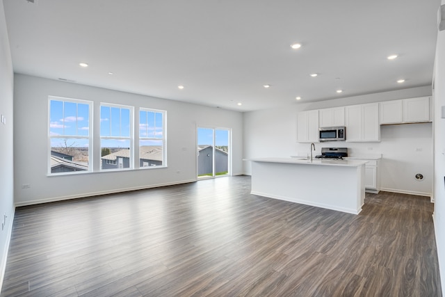 kitchen with dark wood-style flooring, recessed lighting, appliances with stainless steel finishes, open floor plan, and white cabinetry