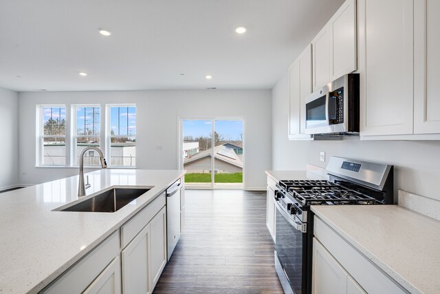 kitchen with dark wood-type flooring, stainless steel appliances, white cabinetry, a sink, and recessed lighting