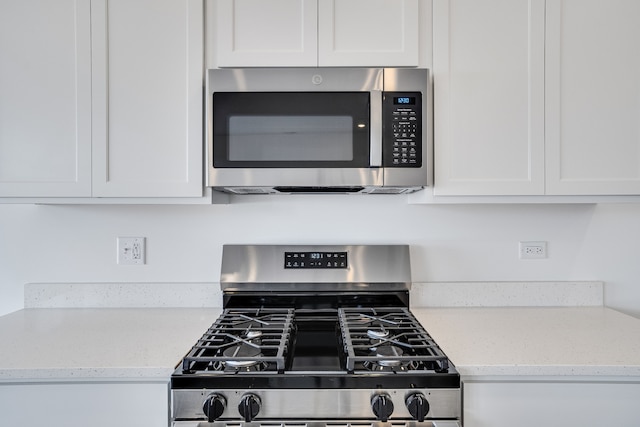 kitchen featuring appliances with stainless steel finishes, white cabinetry, and light stone countertops