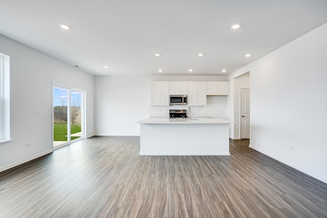 kitchen with appliances with stainless steel finishes, open floor plan, white cabinets, and wood finished floors