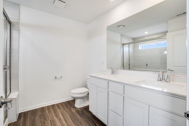 full bathroom featuring a tile shower, wood finished floors, a sink, and visible vents