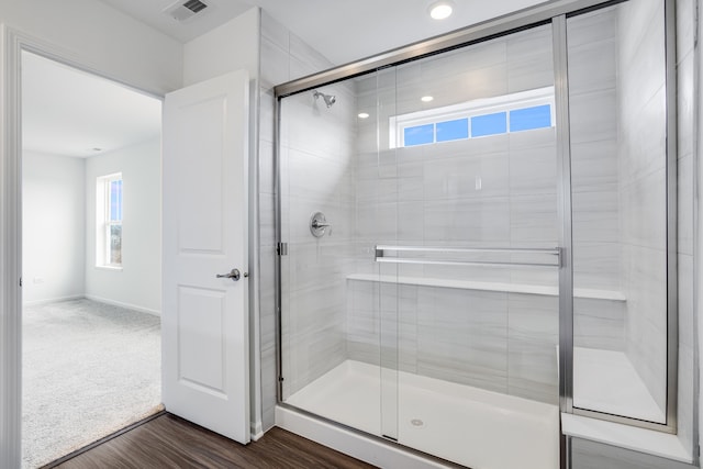 full bath with wood finished floors, a shower stall, visible vents, and baseboards