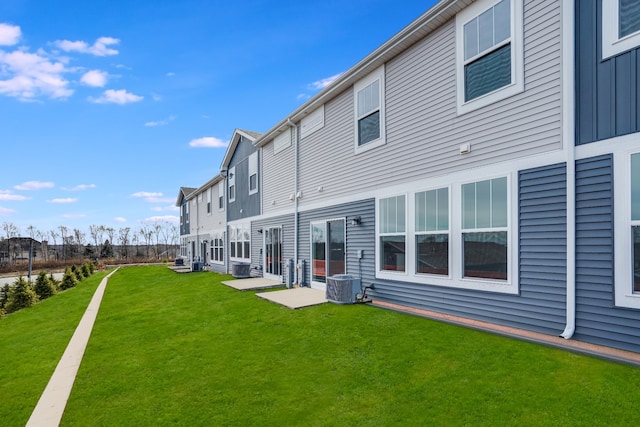 rear view of property with a lawn, board and batten siding, and central air condition unit