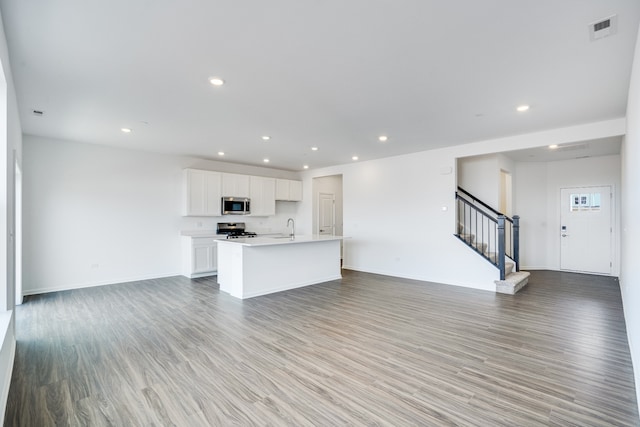 kitchen with visible vents, appliances with stainless steel finishes, open floor plan, light wood-style floors, and white cabinetry