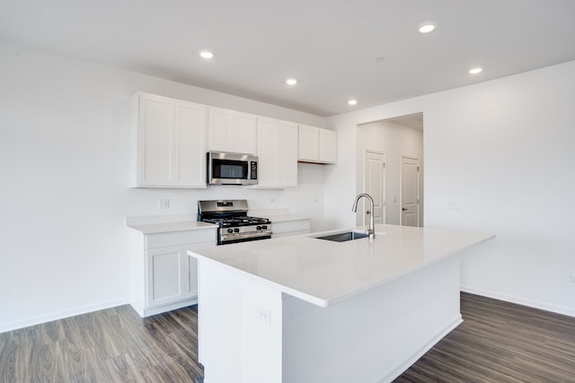 kitchen with dark wood finished floors, a center island with sink, stainless steel appliances, and a sink