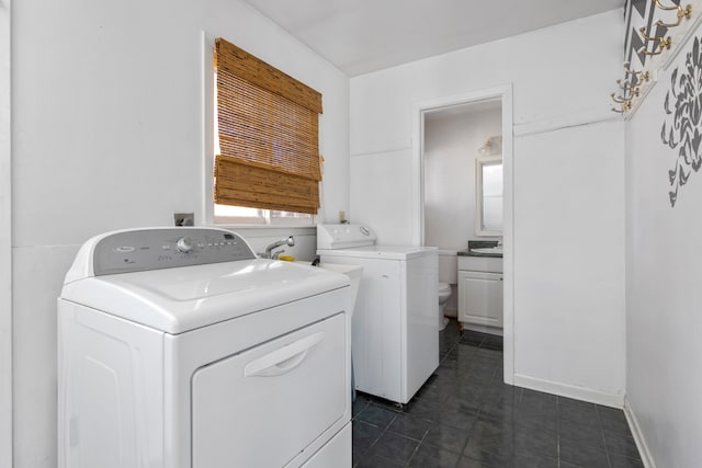 laundry room with independent washer and dryer and dark tile patterned floors