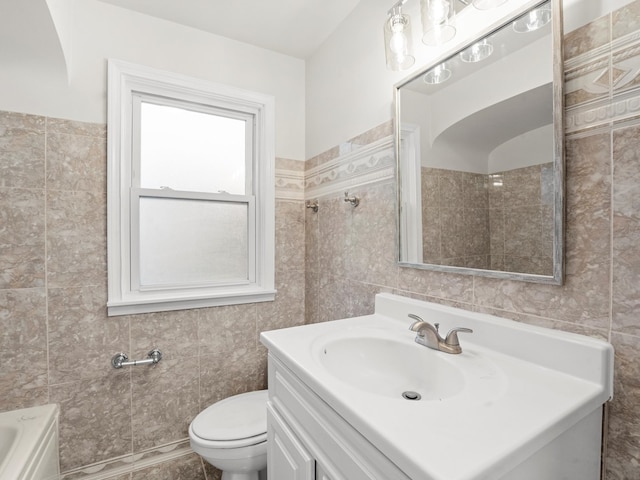 bathroom featuring vanity, toilet, and tile walls