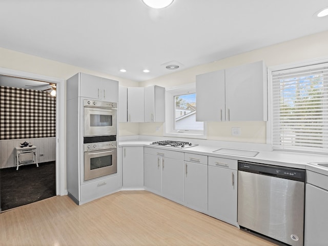 kitchen with ceiling fan, stainless steel appliances, and light hardwood / wood-style flooring