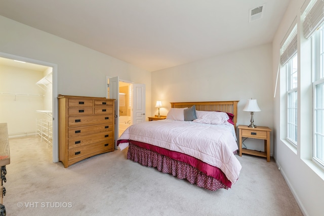 carpeted bedroom with ensuite bath, a closet, and a walk in closet