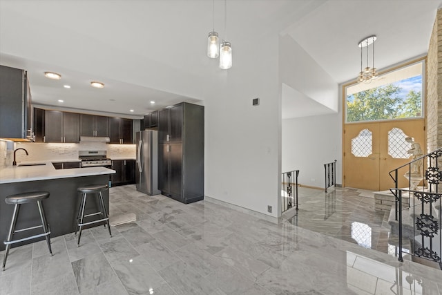 kitchen with appliances with stainless steel finishes, sink, a kitchen bar, kitchen peninsula, and hanging light fixtures