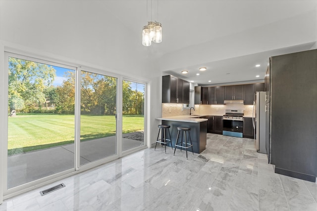 kitchen featuring tasteful backsplash, appliances with stainless steel finishes, a breakfast bar, pendant lighting, and sink