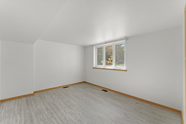 unfurnished room featuring lofted ceiling and light wood-type flooring