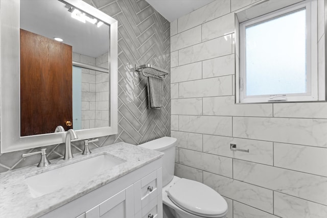 bathroom featuring vanity, toilet, and tile walls