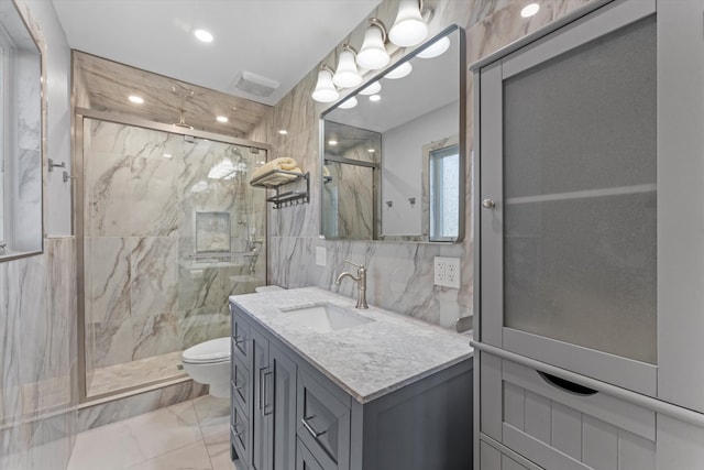 bathroom featuring tile walls, vanity, a shower with shower door, and toilet