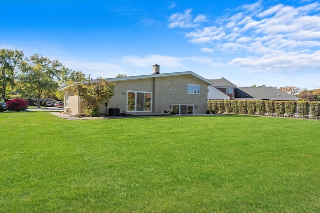 rear view of house featuring central AC and a lawn