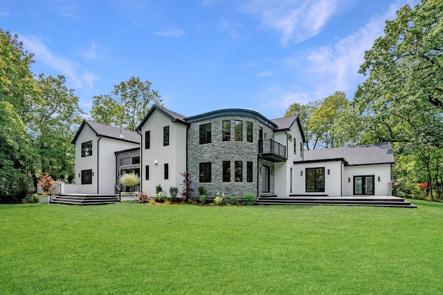 rear view of property featuring a balcony, a yard, and french doors