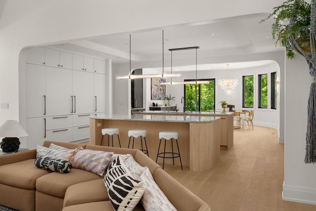 kitchen with a breakfast bar, decorative light fixtures, light hardwood / wood-style flooring, white cabinets, and a center island