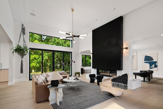 living room with a fireplace, a high ceiling, light hardwood / wood-style floors, and an inviting chandelier