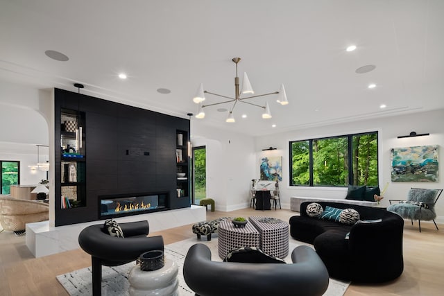 living room with light wood-type flooring, a high end fireplace, and an inviting chandelier