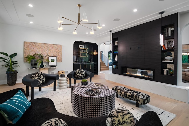 living room with a high end fireplace, an inviting chandelier, and light hardwood / wood-style flooring