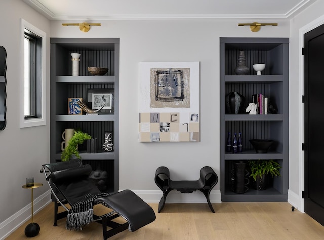 living area featuring hardwood / wood-style floors, built in shelves, and crown molding