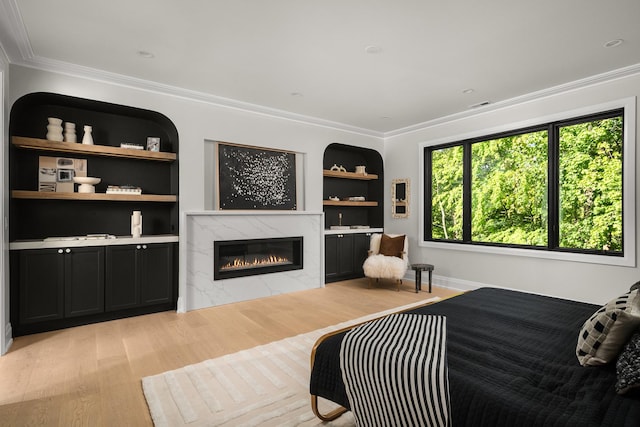 bedroom featuring a fireplace, crown molding, and light hardwood / wood-style flooring