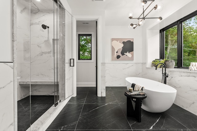 bathroom with separate shower and tub, an inviting chandelier, and tile walls