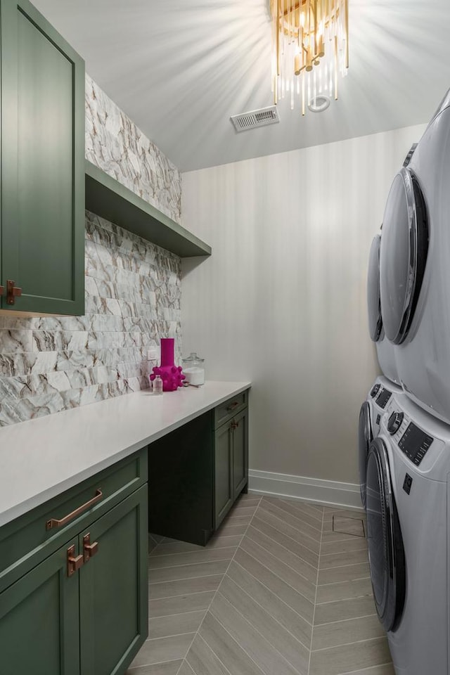 washroom featuring light tile patterned floors, cabinets, stacked washer and clothes dryer, and an inviting chandelier