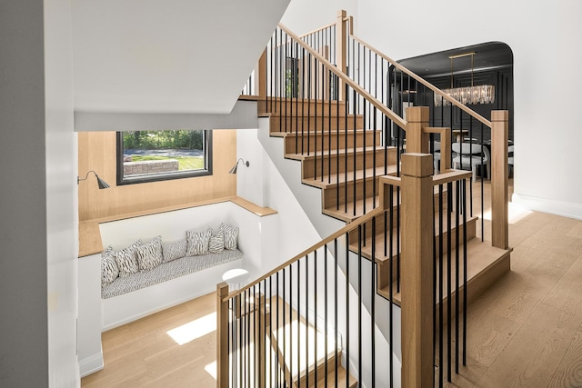 stairs with hardwood / wood-style floors and an inviting chandelier