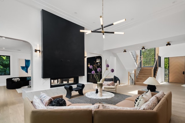 living room with light wood-type flooring, a high ceiling, a wealth of natural light, and an inviting chandelier