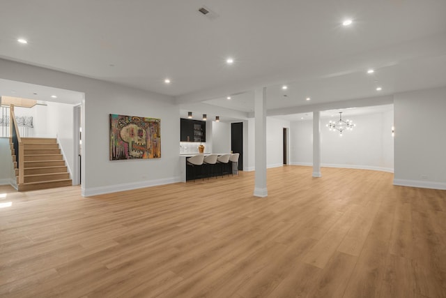 basement with a chandelier and light hardwood / wood-style flooring