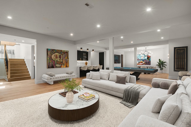 living room with a notable chandelier, pool table, and light hardwood / wood-style flooring