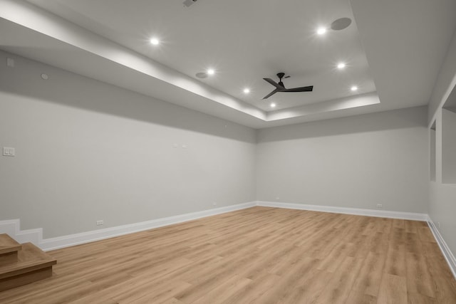 unfurnished room with a raised ceiling, ceiling fan, and light hardwood / wood-style floors