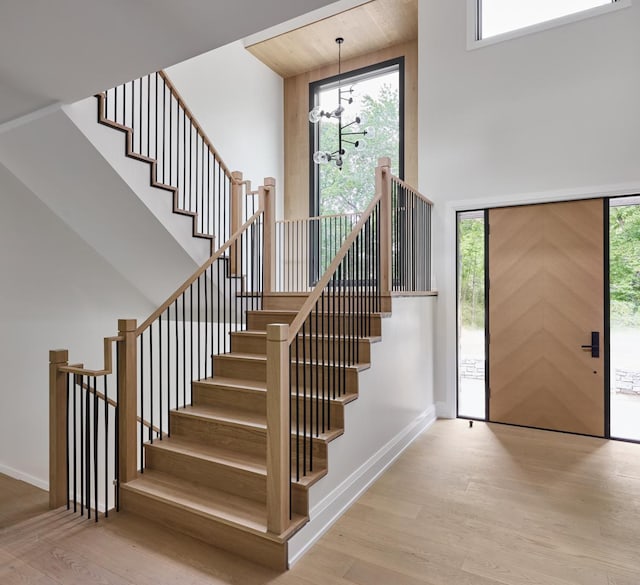 foyer with a notable chandelier, a healthy amount of sunlight, light wood-type flooring, and a towering ceiling