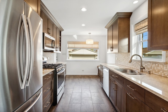 kitchen featuring a wealth of natural light, appliances with stainless steel finishes, sink, and hanging light fixtures