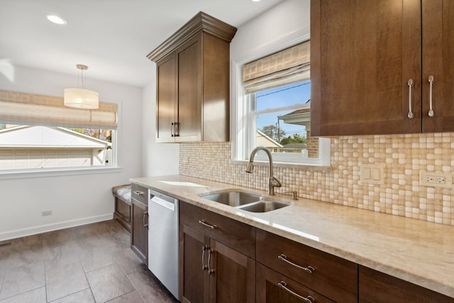 kitchen with stainless steel dishwasher, a healthy amount of sunlight, sink, and light stone counters