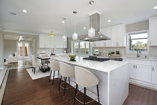 kitchen featuring island exhaust hood, sink, decorative light fixtures, plenty of natural light, and white cabinetry