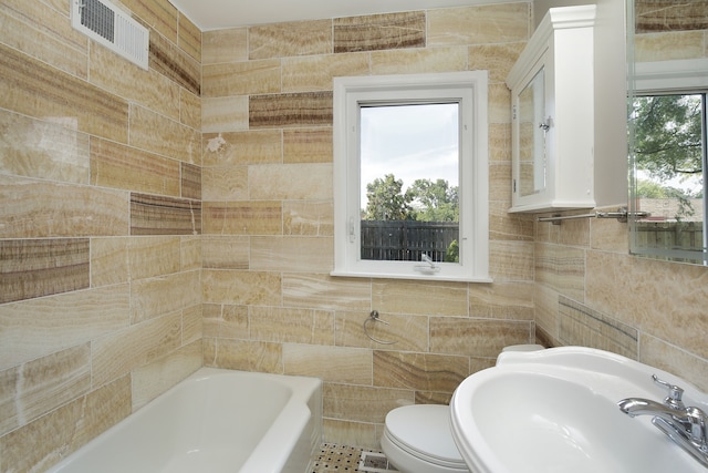 bathroom with toilet, tile walls, sink, and a bath