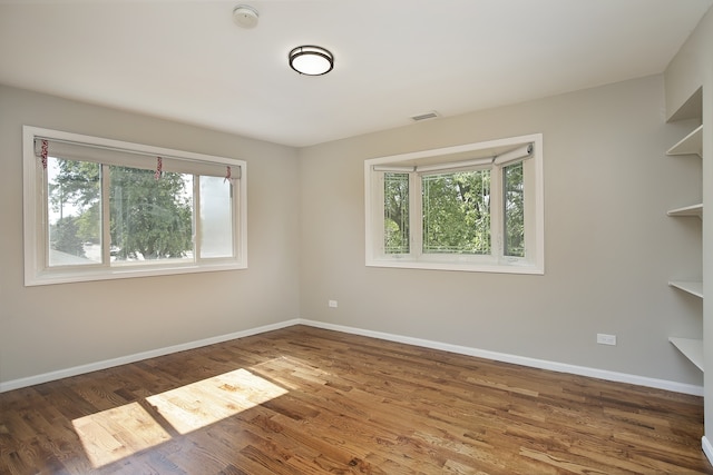 unfurnished room with a wealth of natural light and dark wood-type flooring