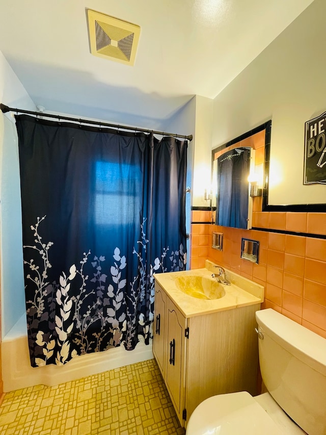 full bathroom with vanity, toilet, tile walls, and shower / tub combo