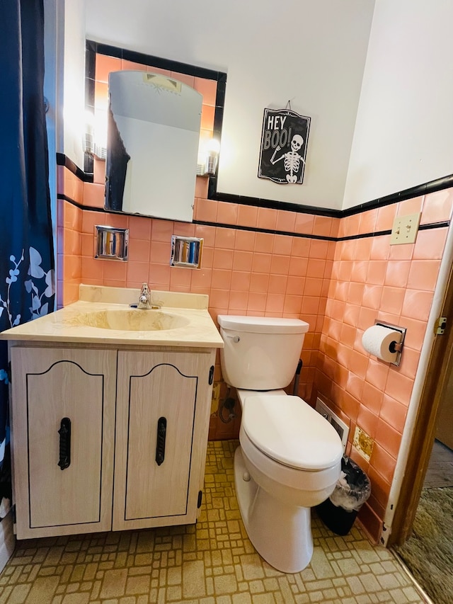 bathroom with tile walls, vanity, and toilet