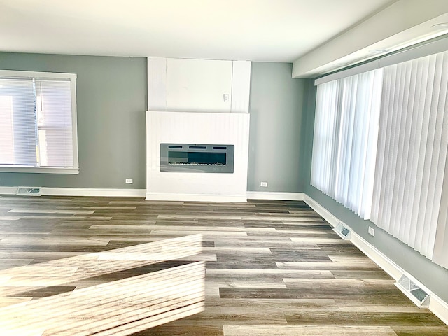 unfurnished living room featuring hardwood / wood-style flooring and heating unit