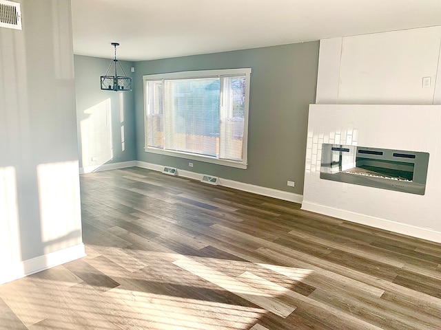 unfurnished dining area featuring hardwood / wood-style floors, heating unit, and a chandelier