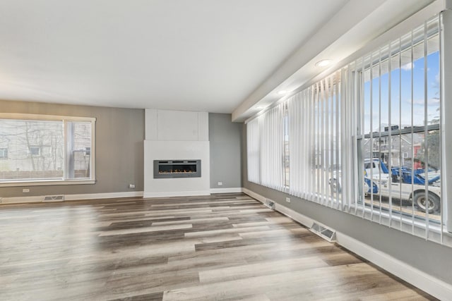 unfurnished living room featuring a large fireplace and light hardwood / wood-style flooring