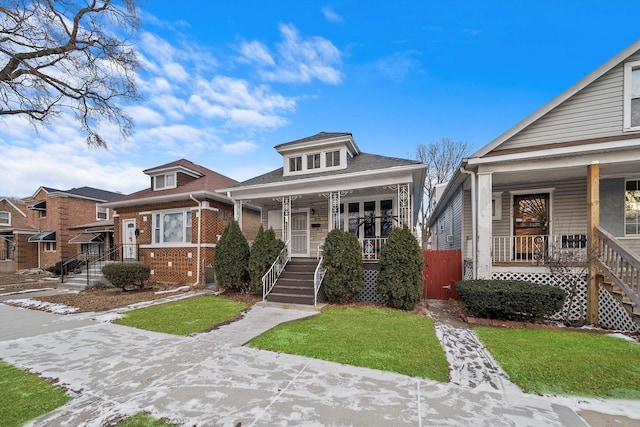 view of front of property featuring a front yard, covered porch, and brick siding